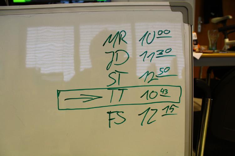 Ein Whiteboard, auf dem verschiedene Uhrzeiten notiert sind.