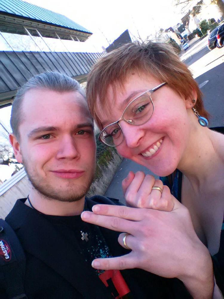 Das frische Ehepaar Lisa und Micha präsentiert die Eheringe; nach der Hochzeit – vor dem Standesamt.